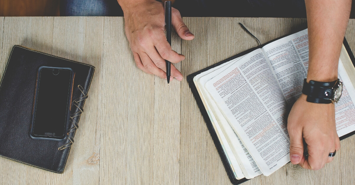 a man holding bible and pen