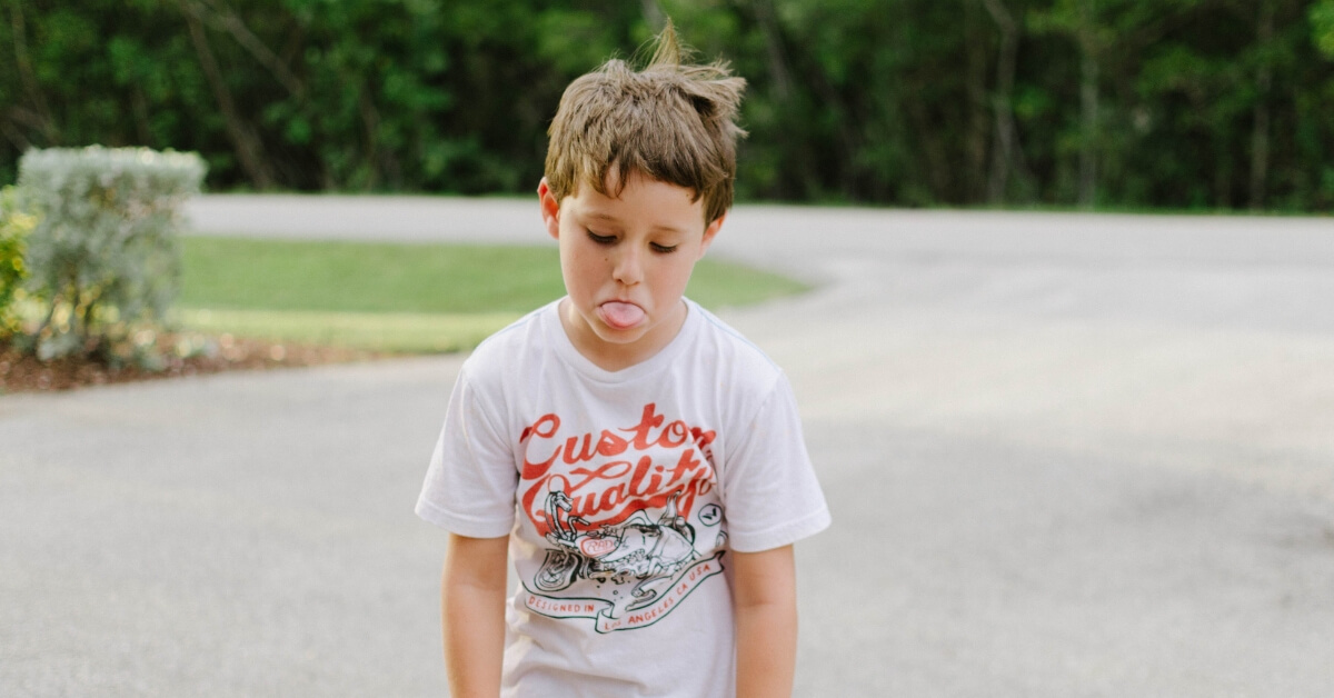 boy with slumped shoulders poking his tongue out