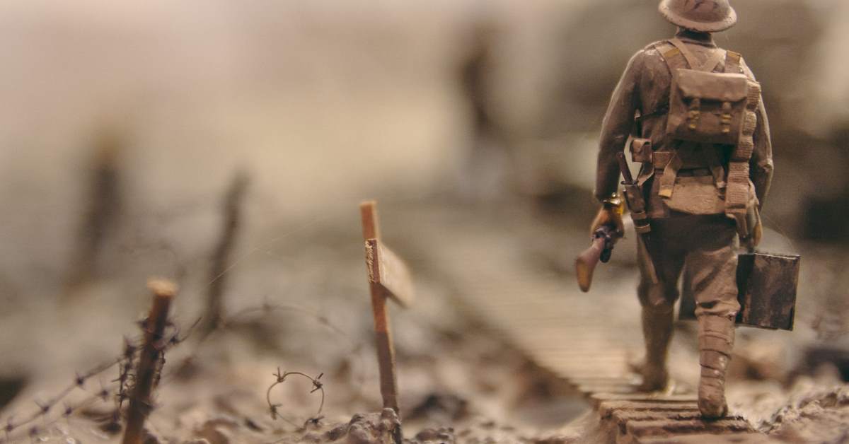 soldier walking on wooden pathway surrounded with barbwire