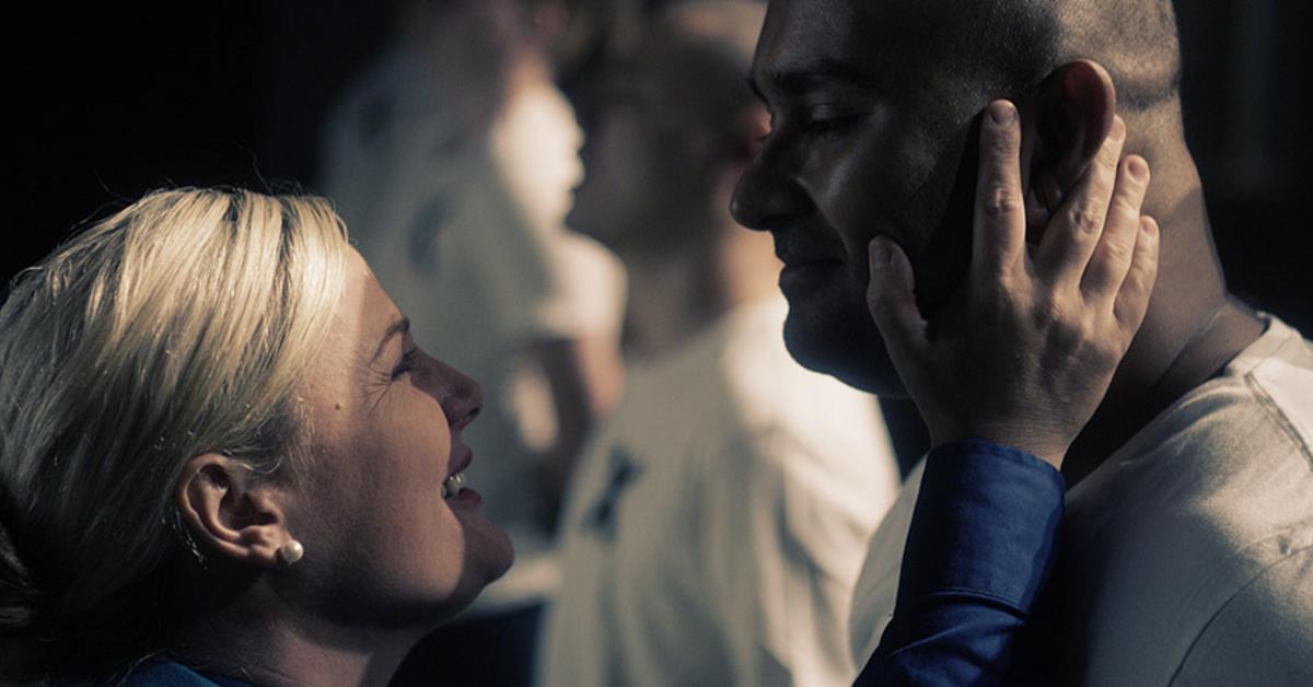 female holding male prisoner's head in her hands and smiling at him