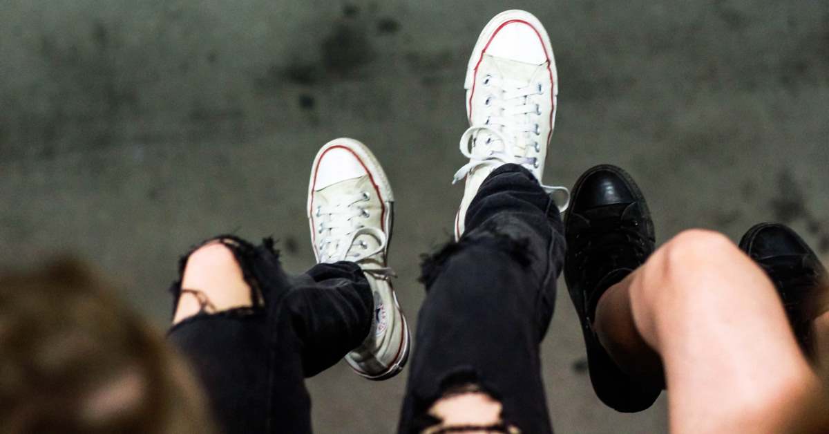 Legs with ripped jeans and converse sneakers hanging over the edge