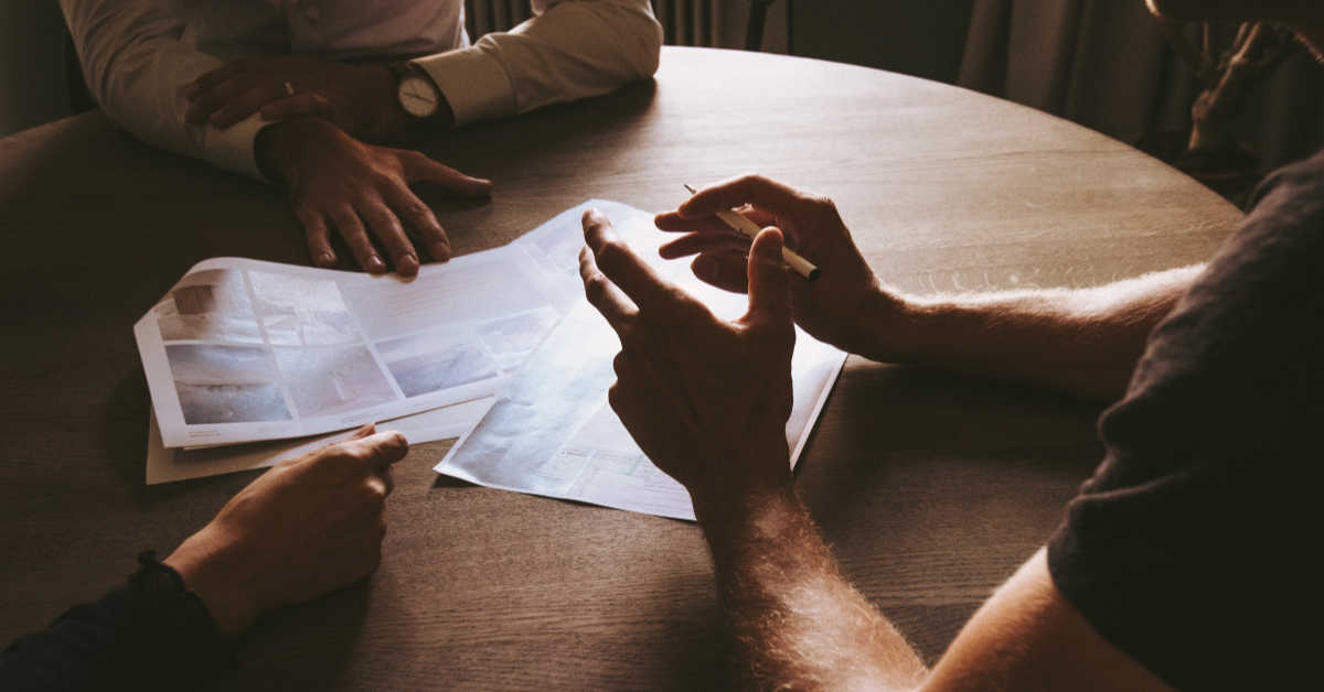 People sitting at table discussing plans on paper