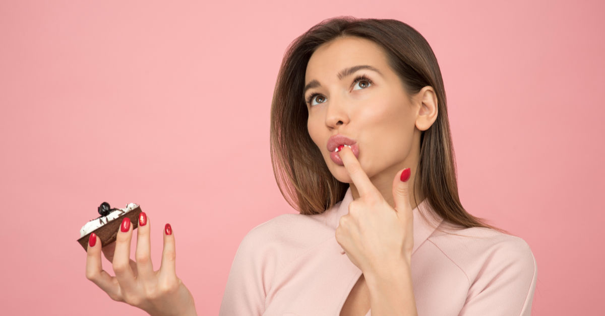 Woman licking cream from cake off her finger