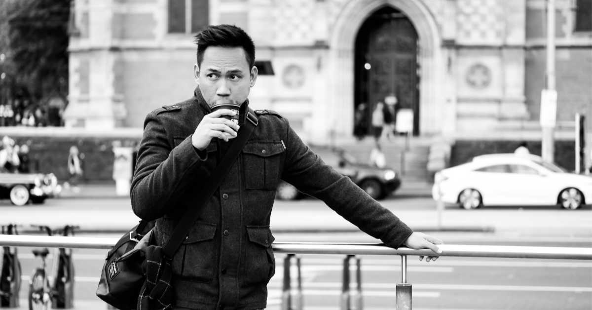 Man drinking coffee outside church in Melbourne