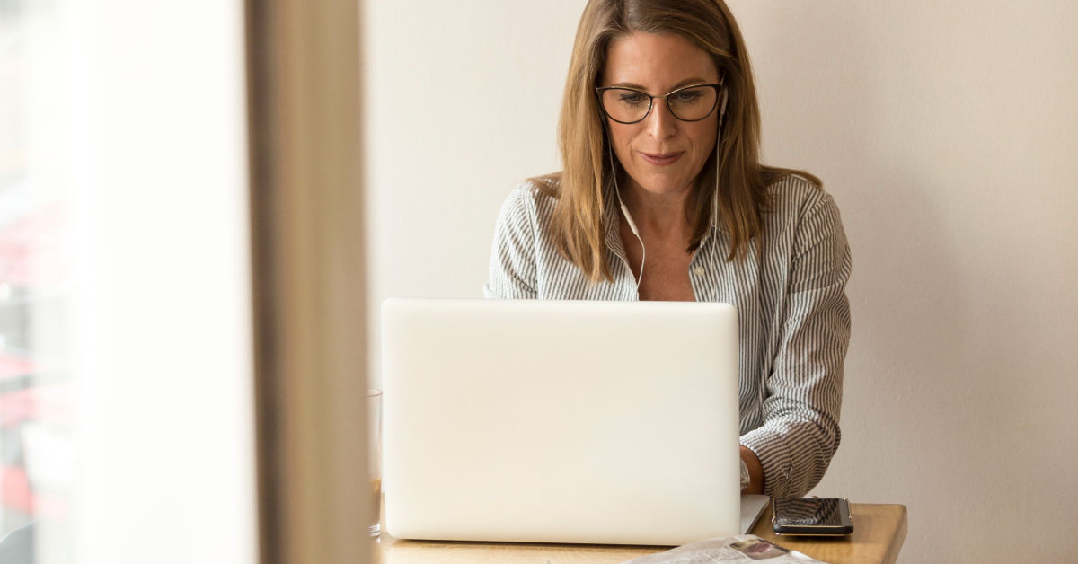 woman writing on laptop in cafe