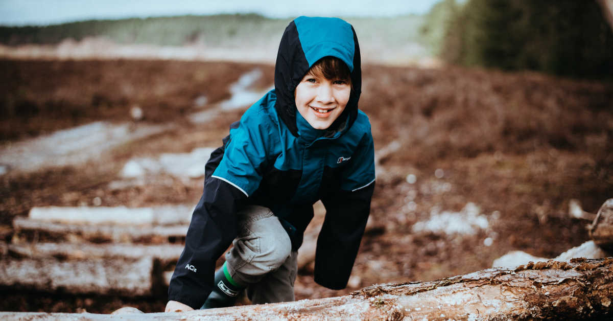 Boy climbing over log