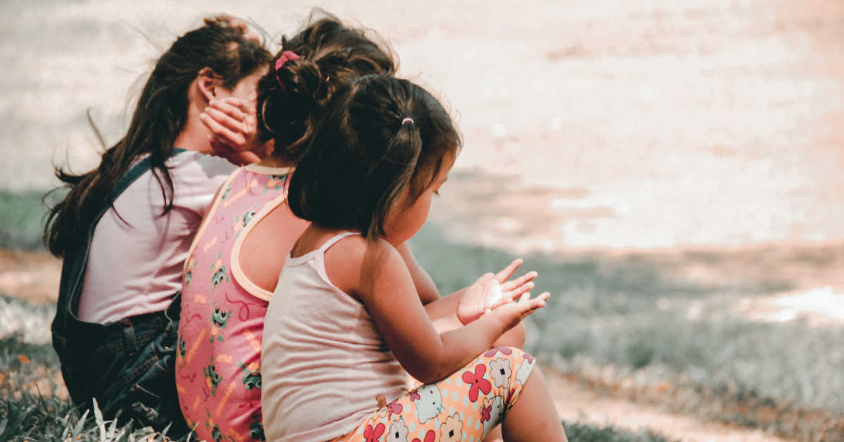 three children sitting on the grass