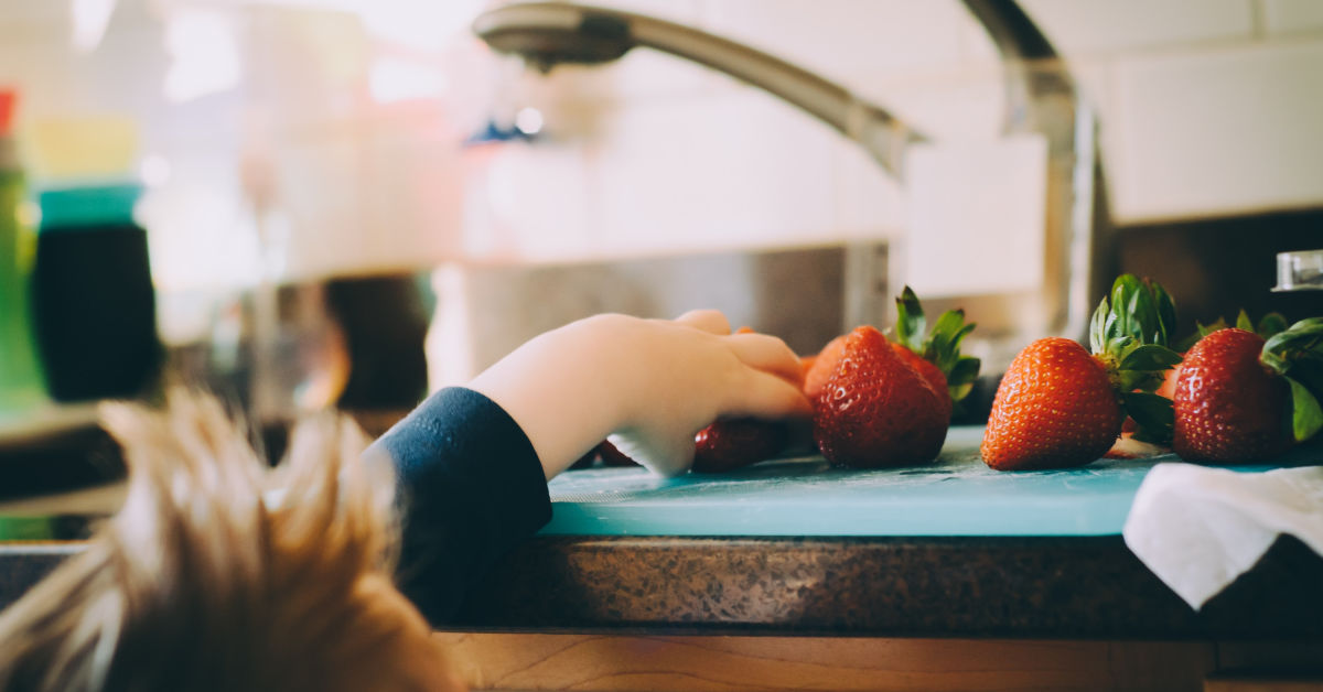 Child reaching for strawberries