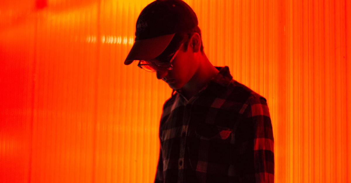 male looking sad head down in front of bright orange wall