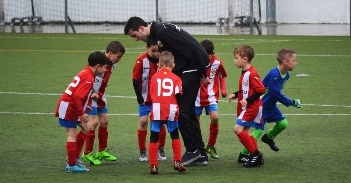 kids playing soccer being talked to by the referee