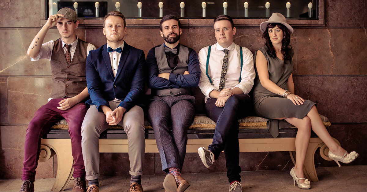 Band of 4 men and 1 women sitting on a bench