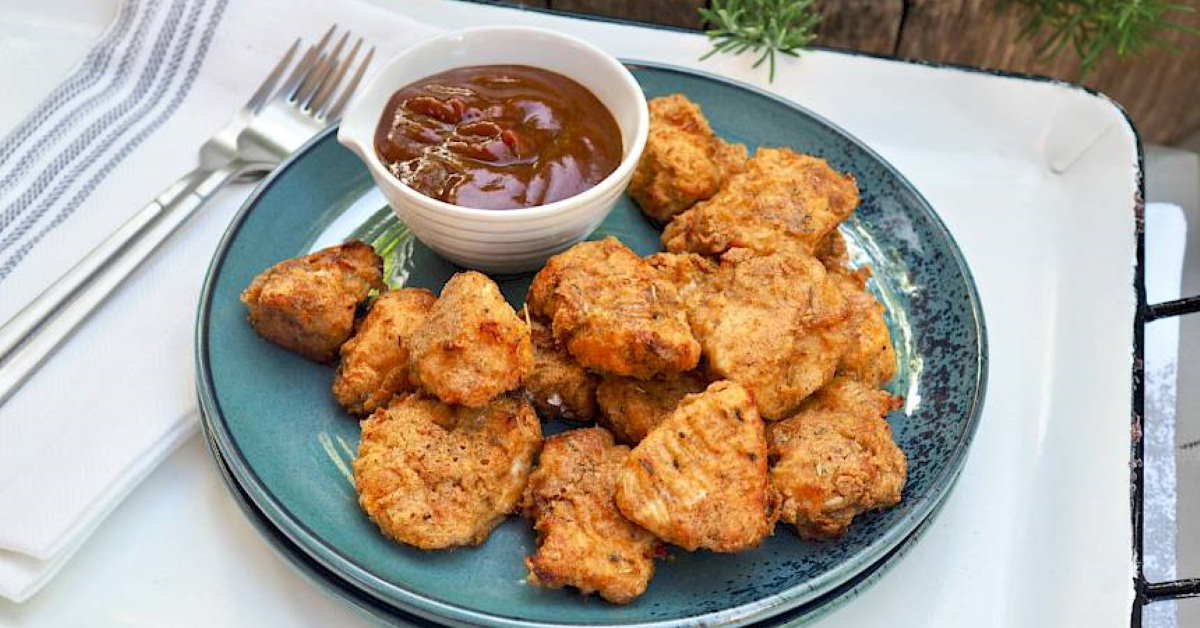 a plate full of chicken nuggets with a bowl of dipping sauce