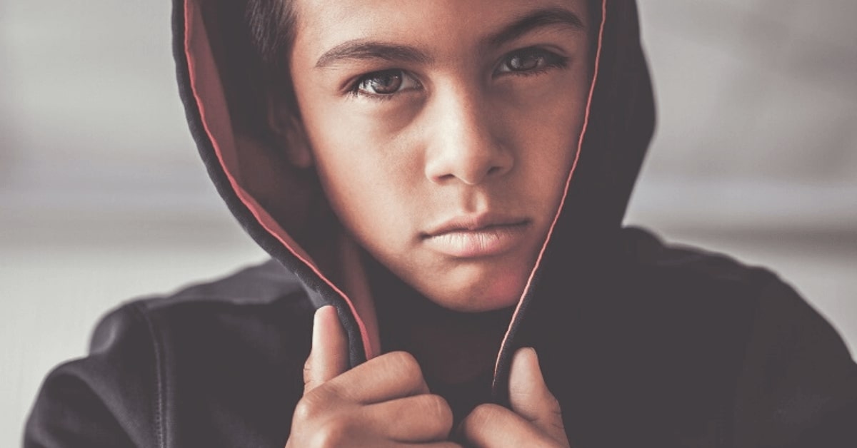 close up of a boy gripping the hood of his jacket