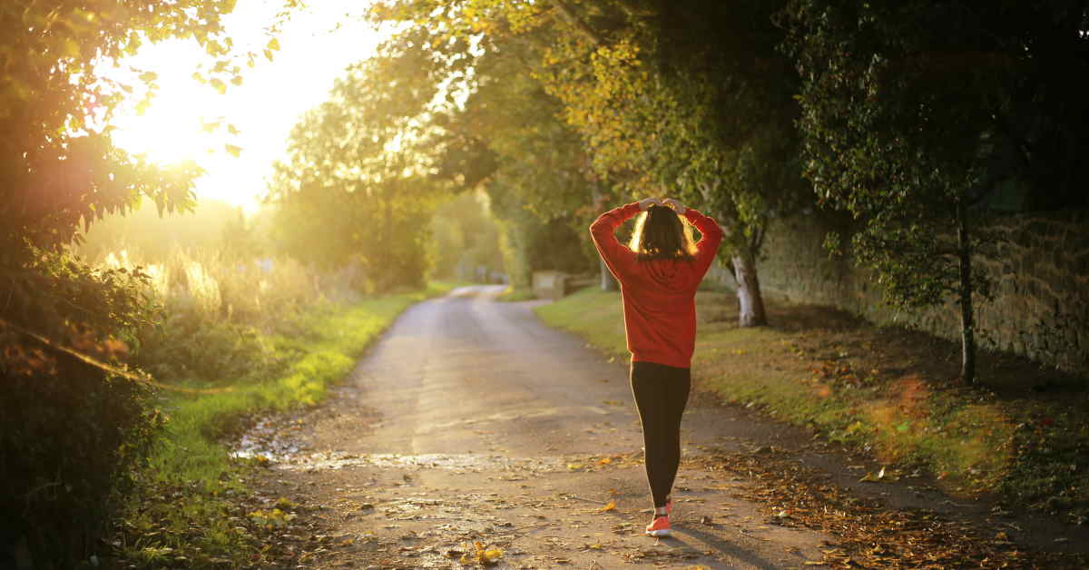 female walking down a sunlit path looking confused