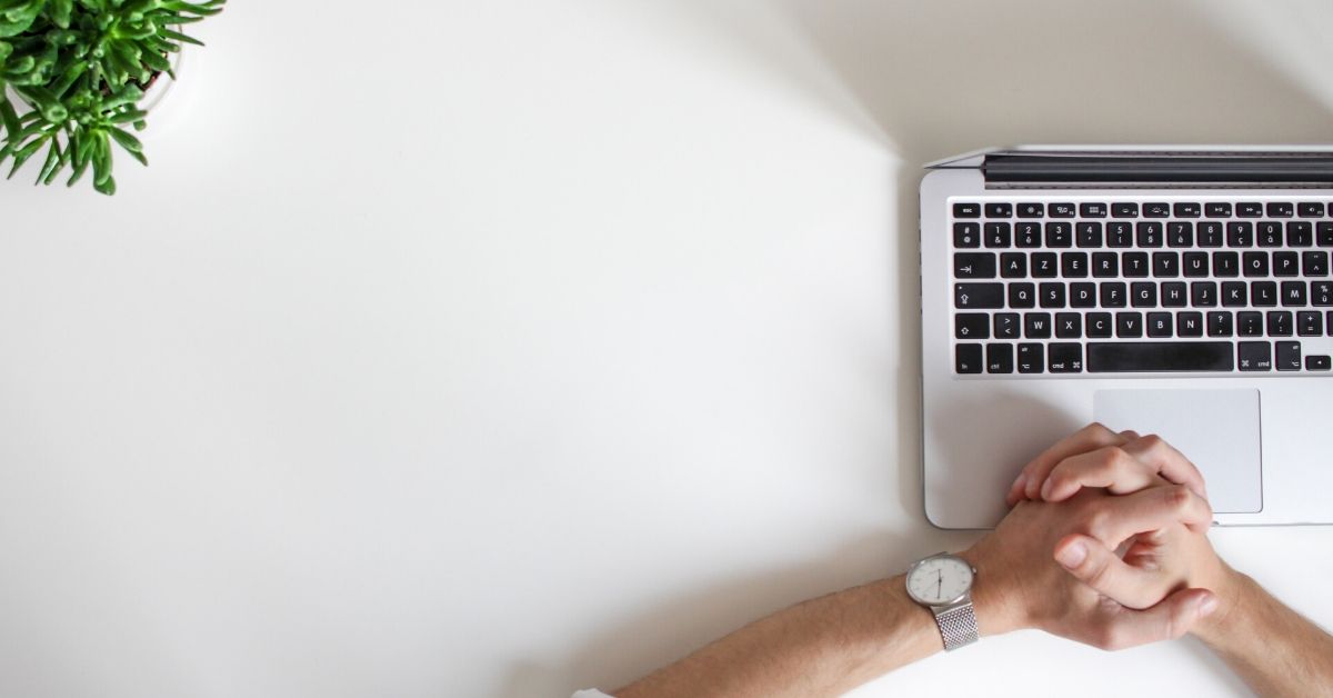 hands clasped on an open laptop