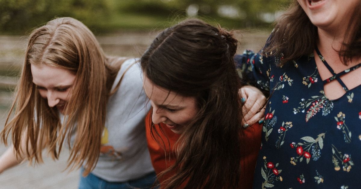 photo of girls laughing and walking together with arms wrapped around each other