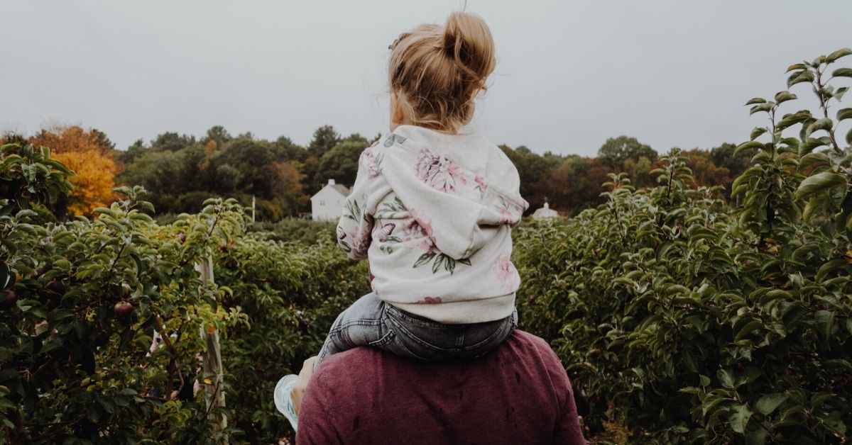 photo of a young girl sitting on her dad's shoulders