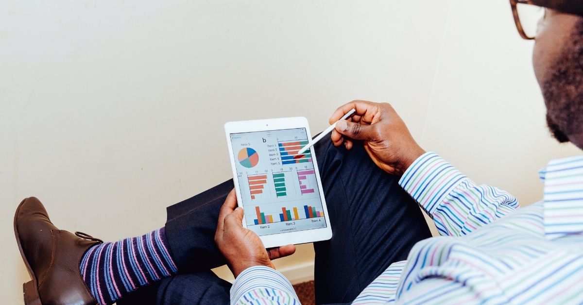 photo of a man looking at a tablet with graphs on it