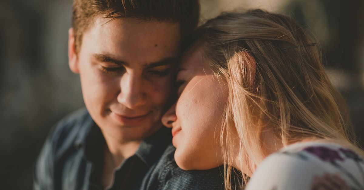 photo of young woman leaning head against young man's shoulder