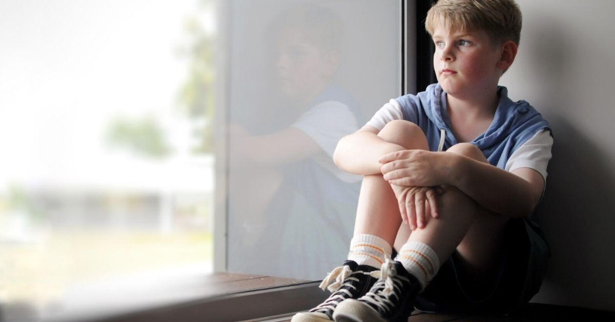 photo of a school aged child looking out the window