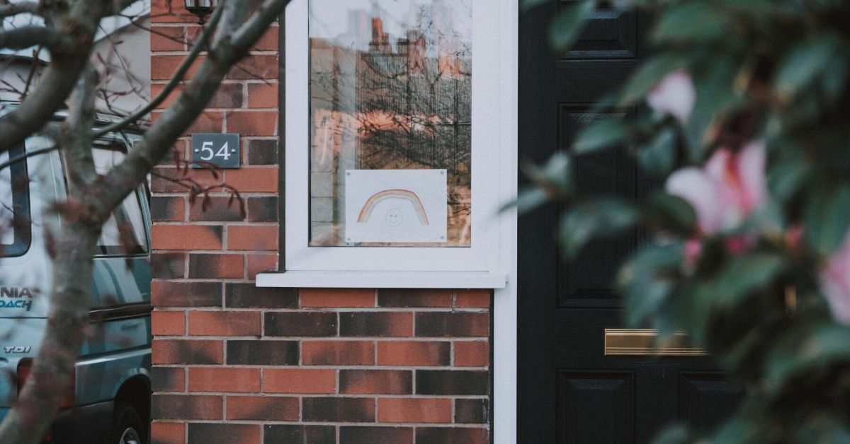 photo of a child's drawing of a rainbow in the window of a house