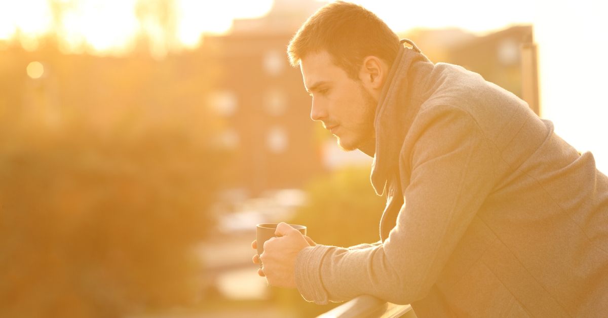 photo of a man leaning over a balcony in thought