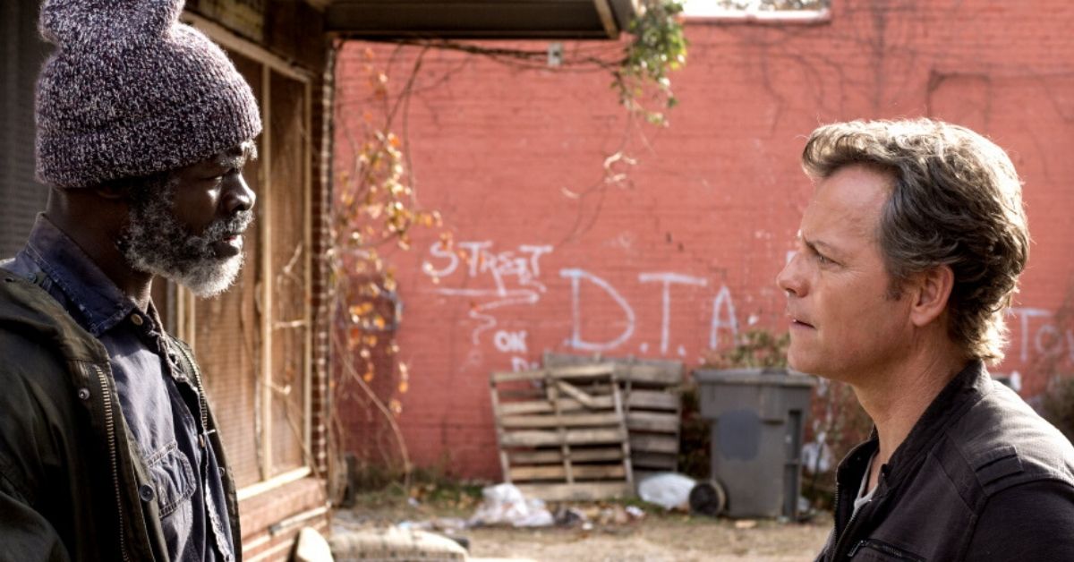 a film still from same kind of different as me featuring Djimon Hounsou who plays Denver and Greg Kinnear who plays Ron talking on the street