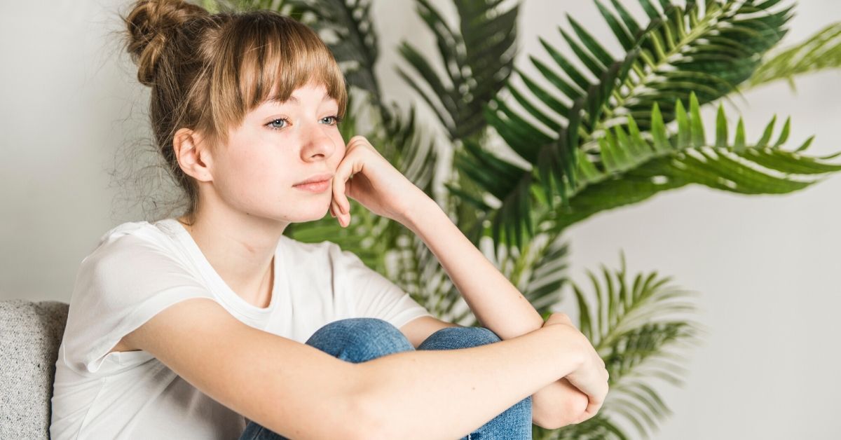 photo of a moody tee sitting in a chair with her fist resting against her chin