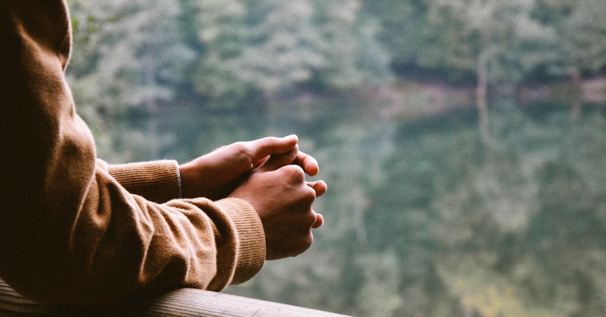 photo of a man leaning on a wooden bannister