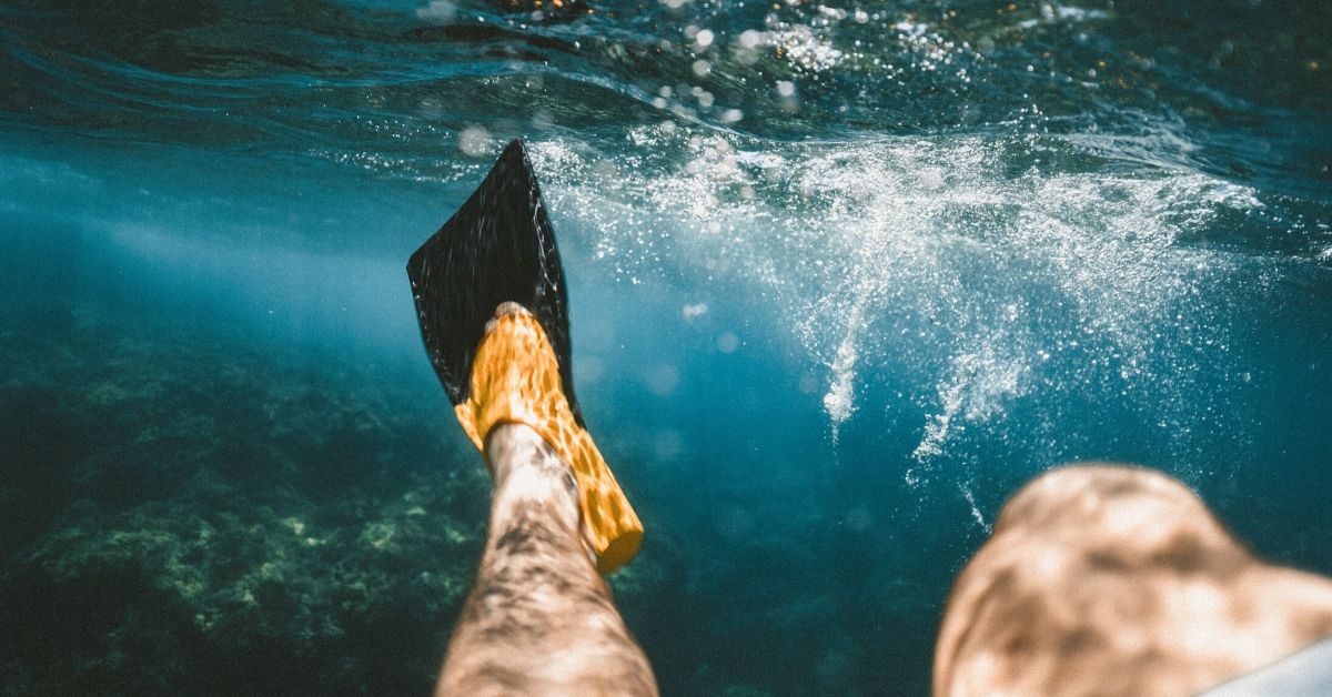 man's flippers underwater stirring the water