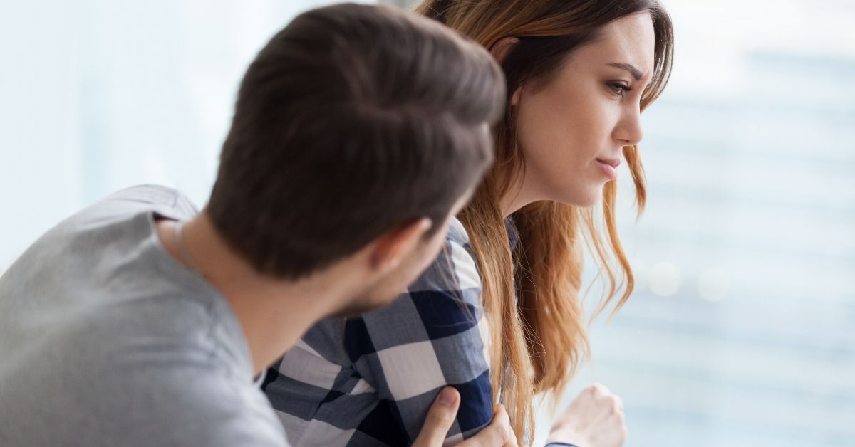 photo of an unhappy woman and a man trying to talk to her