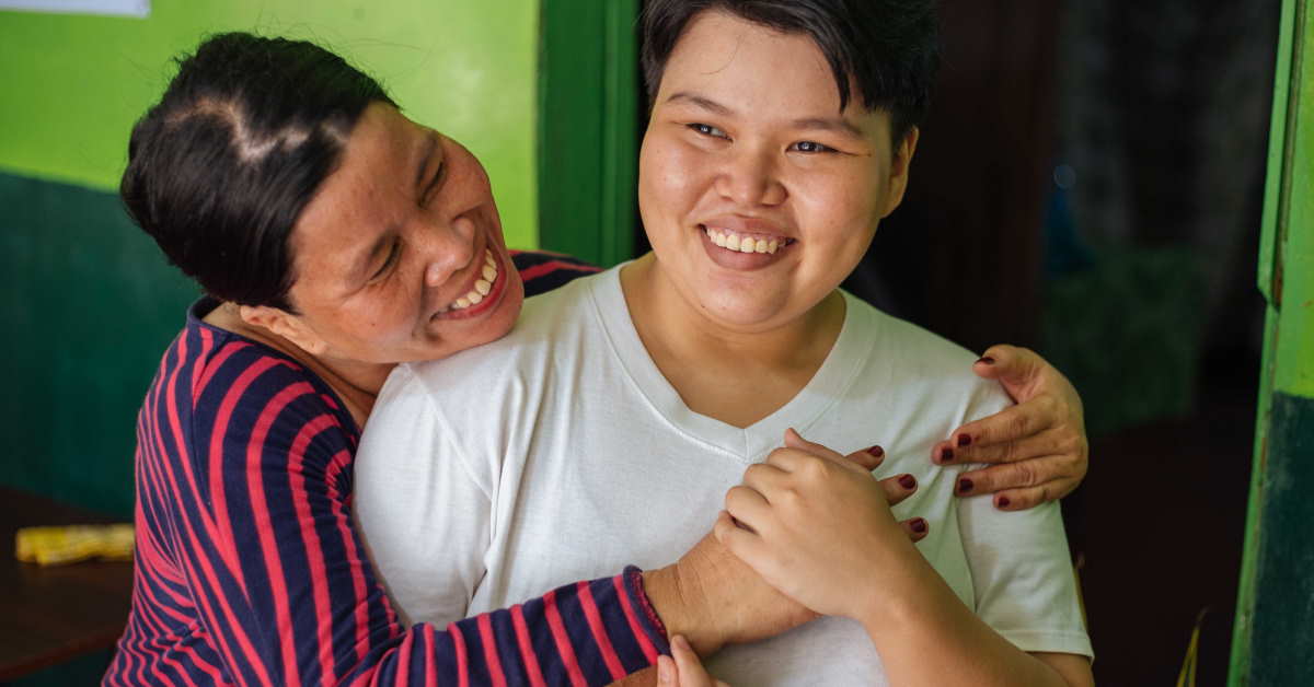 Mum giving daughter hug both have big smiles