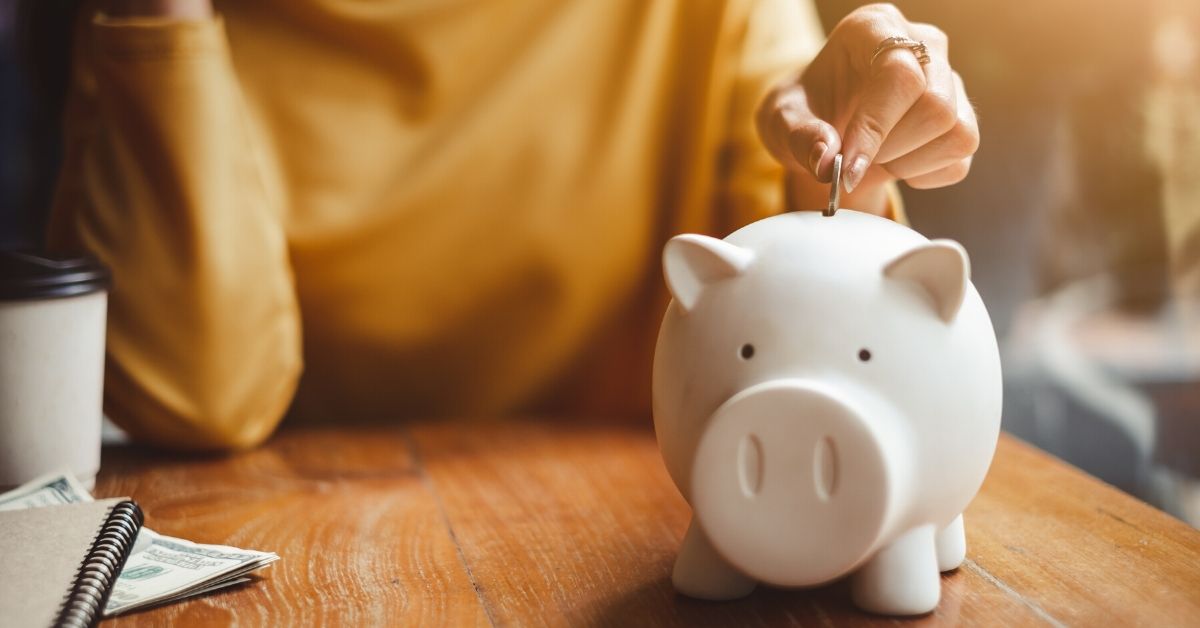 woman puts a coin into a piggy bank