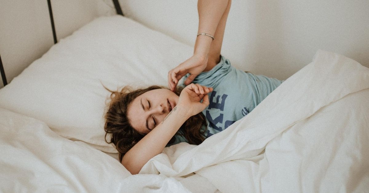 tired woman stretching in bed