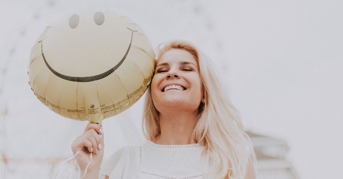 happy girl holding a balloon with a big smiley face on it