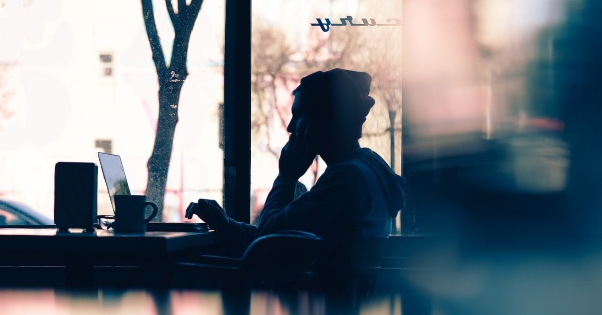 a silhouette of a man talking on the phone in a coffee shop