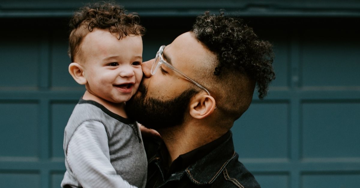 a father holding his son and kissing him lovingly on the cheek