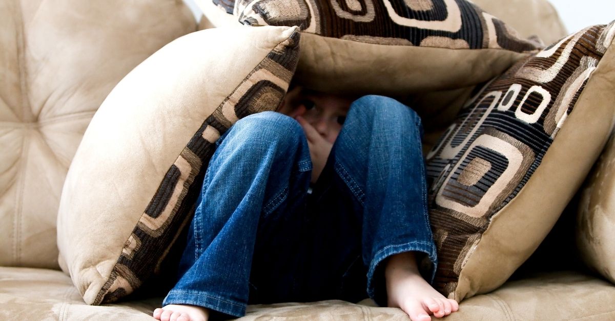 boy hiding under pillows