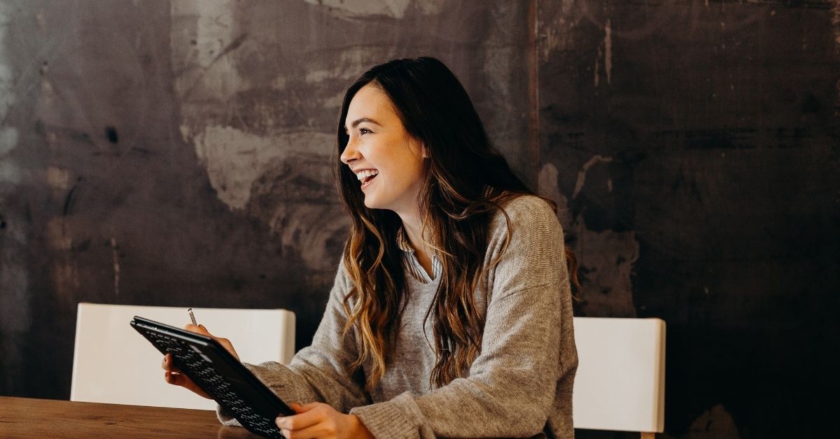 young woman holding an ipad laughing