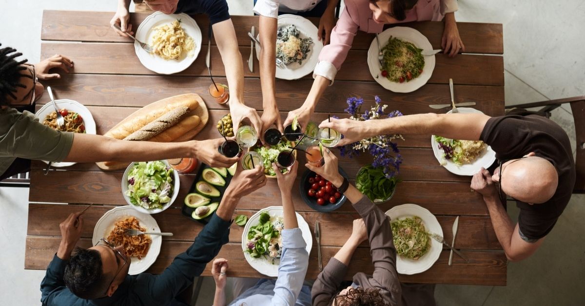 a large diverse family share a meal around a lunch table