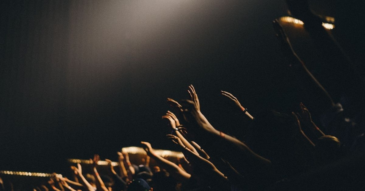 people with hands raised in worship in church