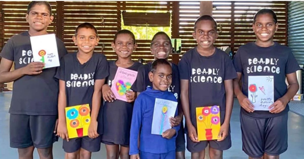 indigenous students smiling and holding hand made mothers day cards