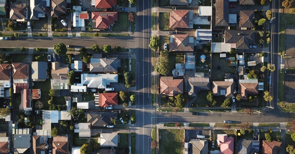 an aerial photo of a suburb during the afternoon with the sun casting shadows across the streets