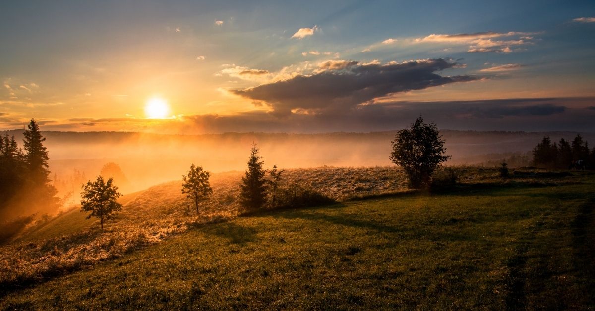 a sunrise over mountains and low hanging clouds