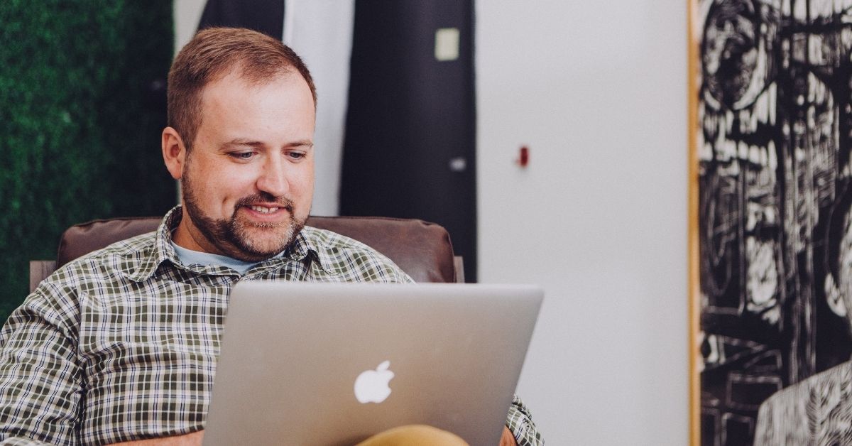 man smiling at his laptop