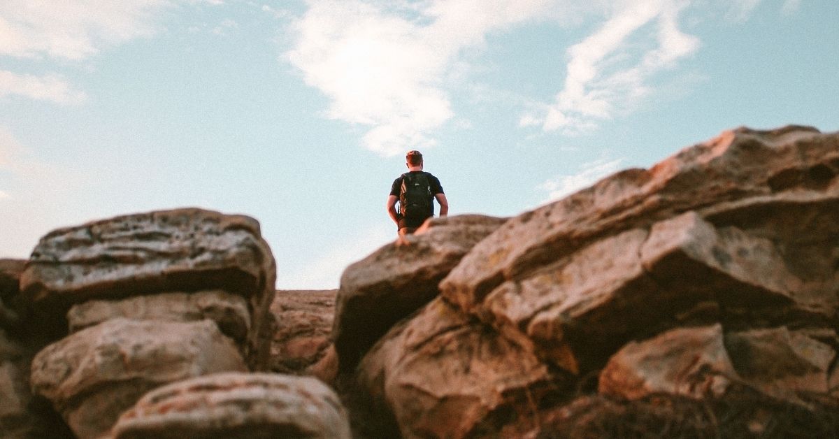 a man hikes up big boulders