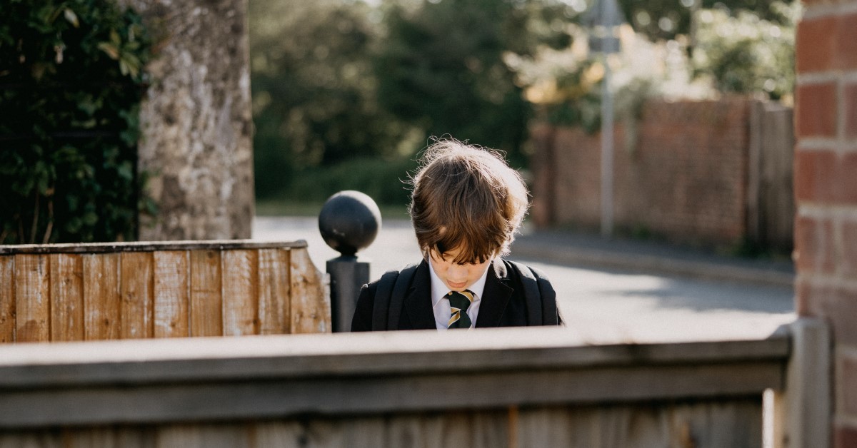 boy in school uniform sitting by himself looking downwards