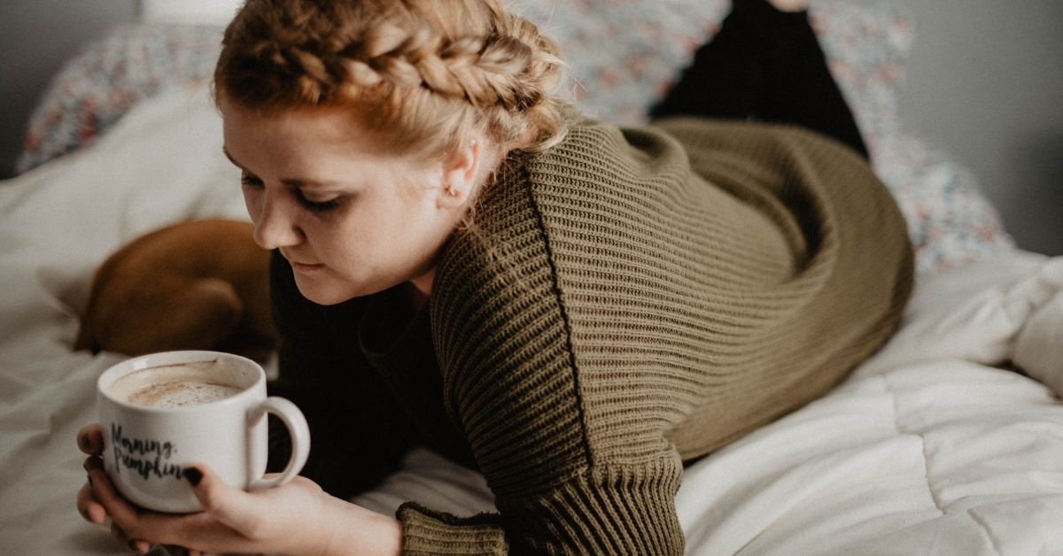 a girl laying in bed with coffee