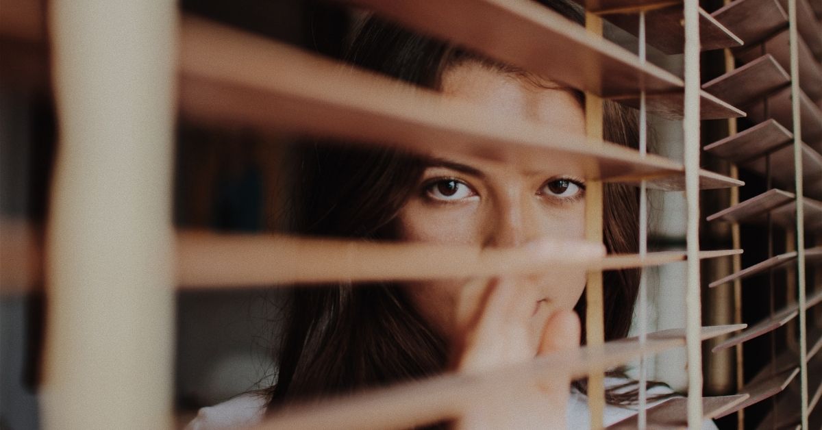 girl peering through blinds