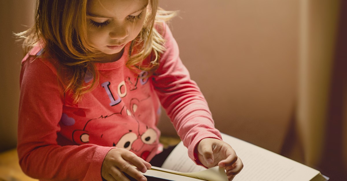 young girl looking through pages of book